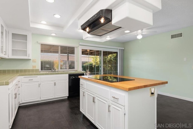 kitchen with a center island, wooden counters, black appliances, ceiling fan, and white cabinetry