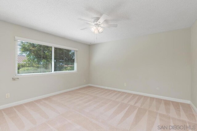 carpeted spare room featuring a textured ceiling and ceiling fan