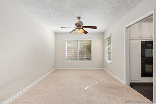 unfurnished dining area with light carpet, ceiling fan, and a textured ceiling