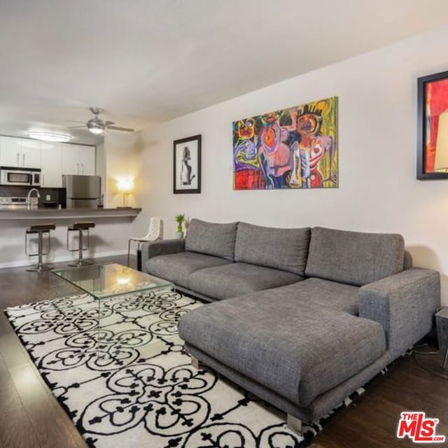 living room with hardwood / wood-style flooring, ceiling fan, and sink