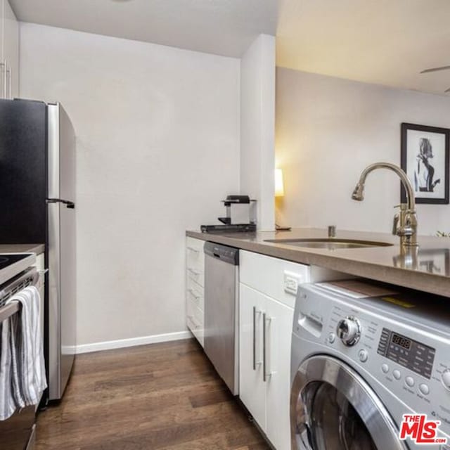 kitchen with sink, dark wood-type flooring, white cabinetry, stainless steel appliances, and washer / dryer