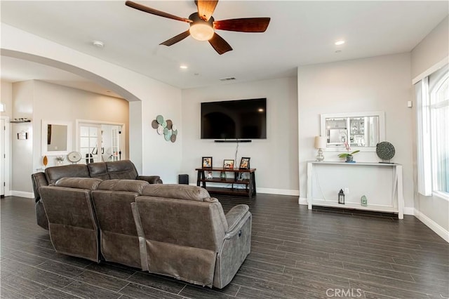 living room featuring dark wood-type flooring, ceiling fan, and a healthy amount of sunlight