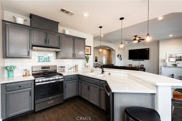 kitchen with kitchen peninsula, a breakfast bar, hanging light fixtures, and appliances with stainless steel finishes