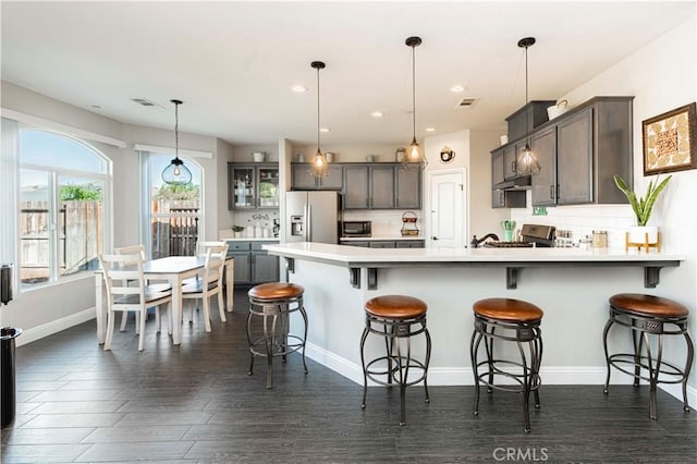 kitchen featuring backsplash, a breakfast bar, decorative light fixtures, and appliances with stainless steel finishes