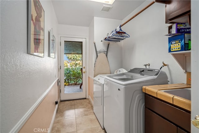 laundry room featuring light tile patterned flooring, washer and clothes dryer, and cabinets