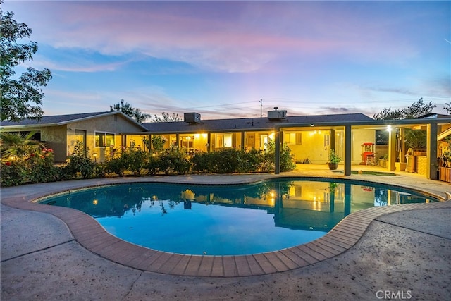 pool at dusk with a patio area