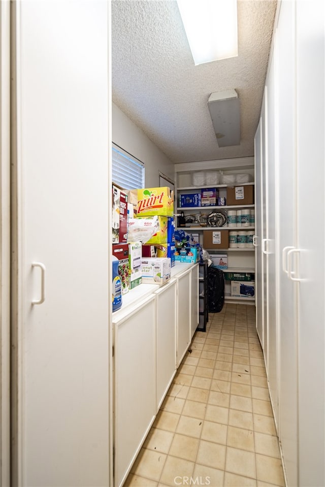 laundry room featuring a textured ceiling and light tile patterned flooring