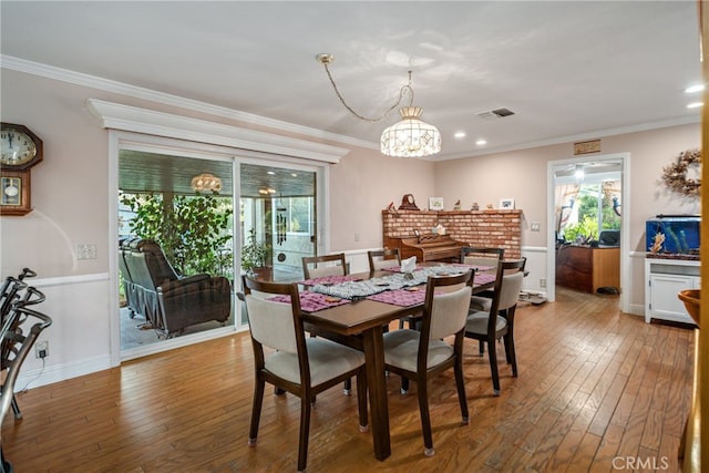 dining space featuring ornamental molding, hardwood / wood-style floors, and a notable chandelier