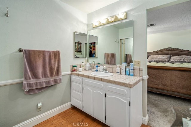 bathroom with vanity, wood-type flooring, and a textured ceiling