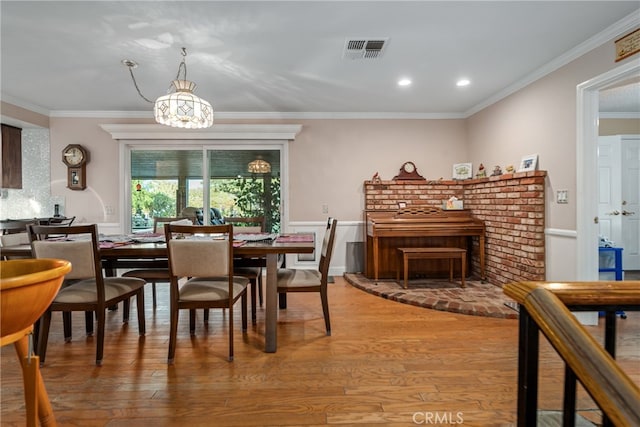 dining area with wood-type flooring, a notable chandelier, and crown molding