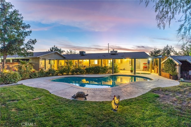 pool at dusk featuring a yard and a patio