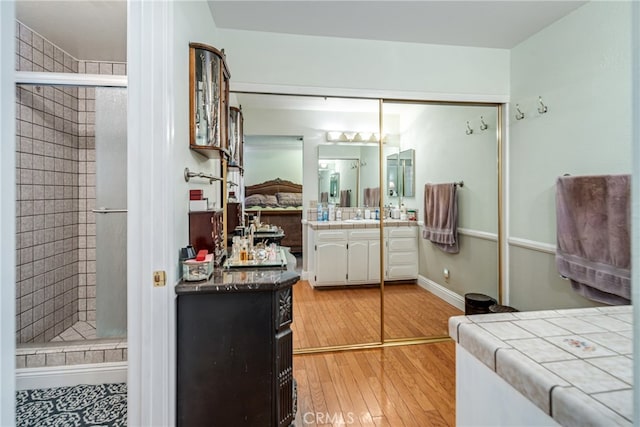 bathroom with wood-type flooring, a shower with shower door, and vanity