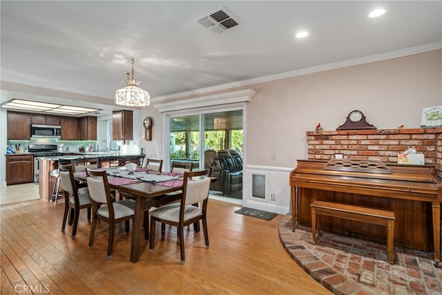 dining area featuring crown molding and light hardwood / wood-style floors