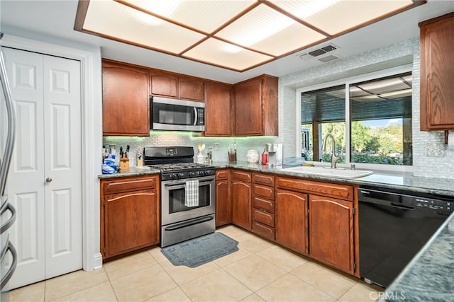 kitchen featuring decorative backsplash, appliances with stainless steel finishes, sink, and light tile patterned floors