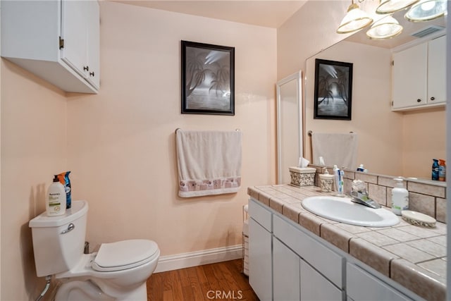 bathroom with hardwood / wood-style flooring, vanity, toilet, and backsplash