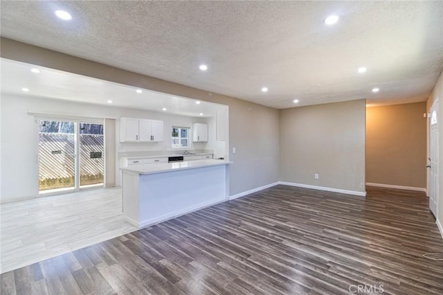 kitchen featuring kitchen peninsula, hardwood / wood-style floors, a textured ceiling, and white cabinetry