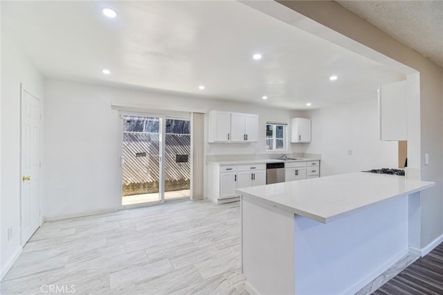 kitchen with a breakfast bar, sink, kitchen peninsula, stainless steel dishwasher, and white cabinetry