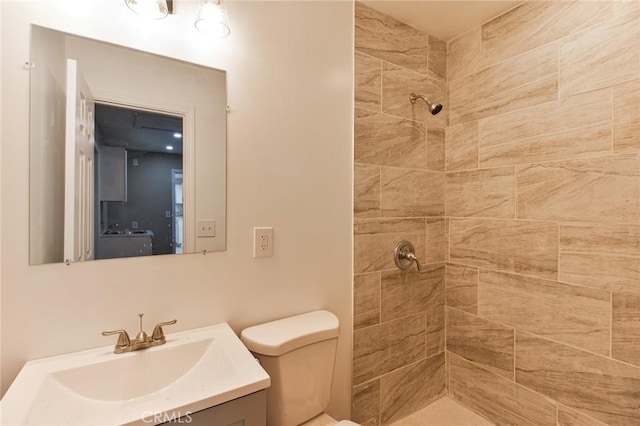 bathroom with toilet, vanity, and tiled shower