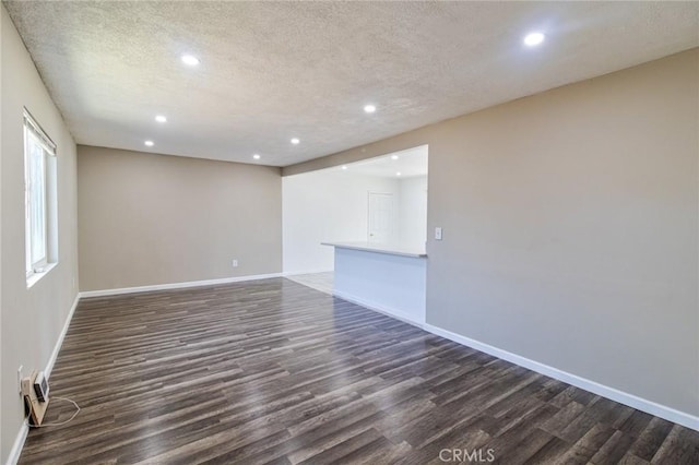 empty room with dark wood-type flooring and a textured ceiling