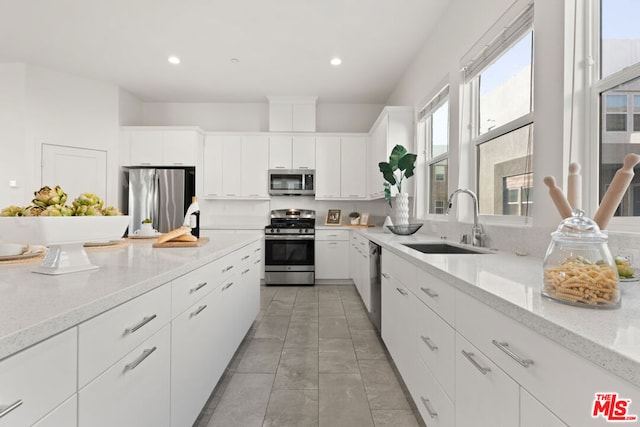 kitchen with light stone countertops, sink, white cabinets, and appliances with stainless steel finishes