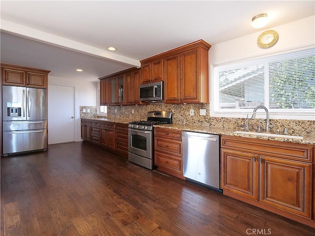 kitchen featuring decorative backsplash, light stone counters, stainless steel appliances, sink, and dark hardwood / wood-style floors