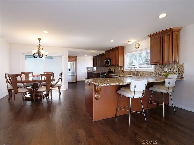 kitchen with hanging light fixtures, tasteful backsplash, dark hardwood / wood-style flooring, stainless steel appliances, and a chandelier