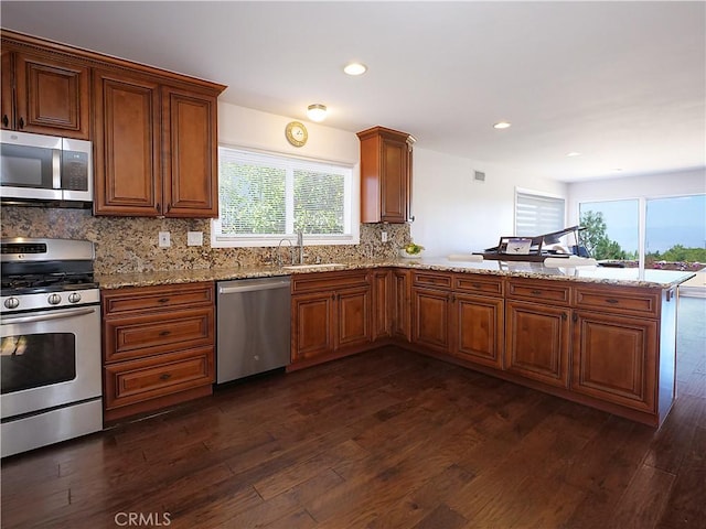 kitchen with dark hardwood / wood-style floors, kitchen peninsula, sink, and appliances with stainless steel finishes