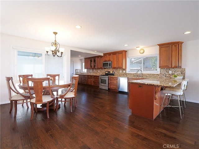 kitchen with sink, stainless steel appliances, dark hardwood / wood-style flooring, a chandelier, and decorative light fixtures