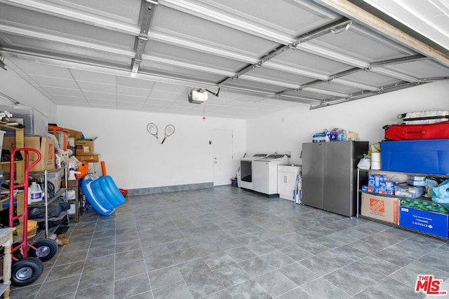 garage with stainless steel fridge, a garage door opener, and washing machine and clothes dryer