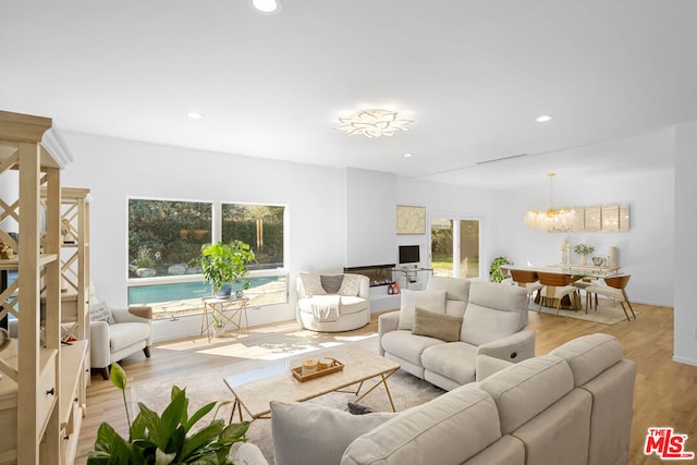 living room featuring light wood-type flooring, a wealth of natural light, and a notable chandelier