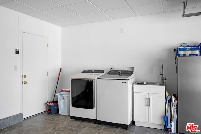 laundry area with washing machine and dryer, sink, dark tile patterned floors, and cabinets