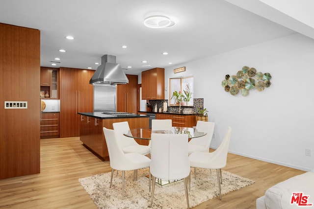 interior space featuring a center island, island range hood, light hardwood / wood-style floors, and tasteful backsplash