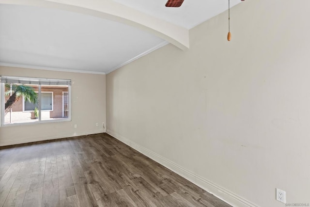 empty room featuring dark wood-type flooring, ceiling fan, ornamental molding, and beam ceiling