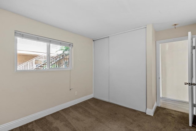 unfurnished bedroom with dark carpet and a closet