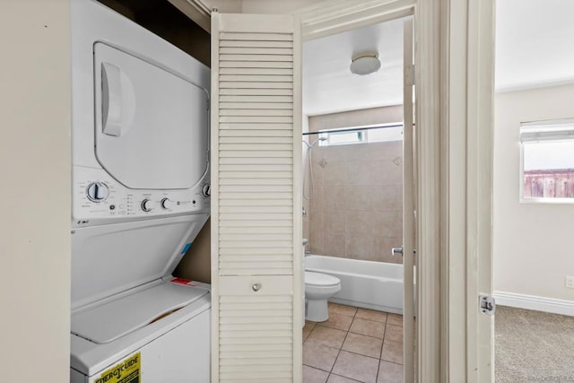 clothes washing area featuring stacked washing maching and dryer, plenty of natural light, and light tile patterned floors