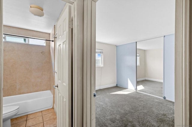 bathroom with toilet, tiled shower / bath combo, and tile patterned flooring