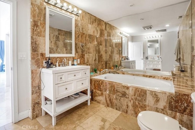 bathroom with vanity, a relaxing tiled tub, tile walls, and toilet