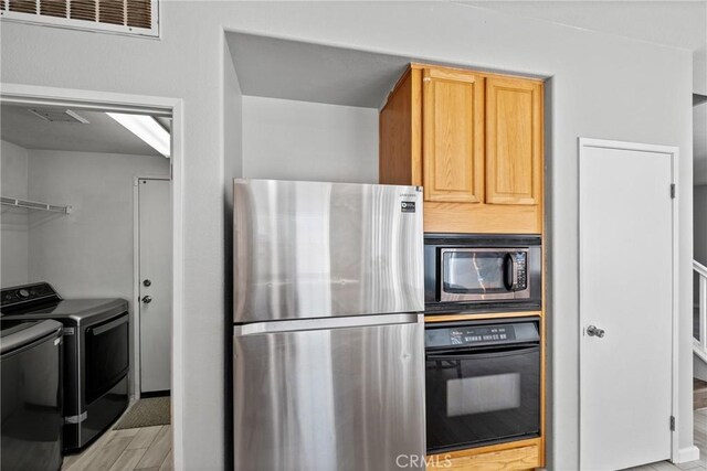 kitchen with separate washer and dryer, light brown cabinetry, stainless steel appliances, and light hardwood / wood-style floors