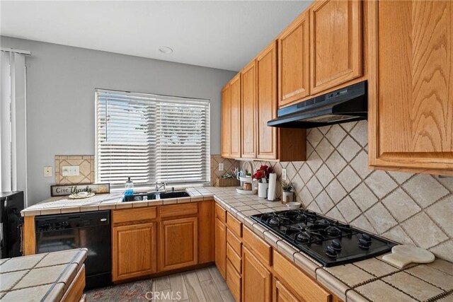 kitchen with backsplash, tile counters, black appliances, and sink