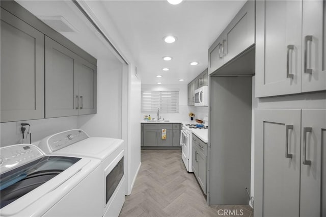 washroom featuring washing machine and dryer, light parquet flooring, and sink