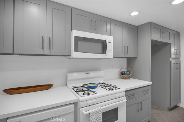 kitchen featuring backsplash, white appliances, and gray cabinetry