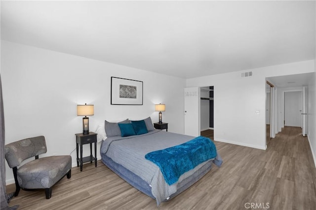 bedroom featuring a spacious closet, hardwood / wood-style floors, and a closet