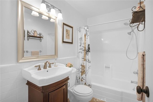 full bathroom featuring tile walls, toilet, vanity, and shower / bath combo