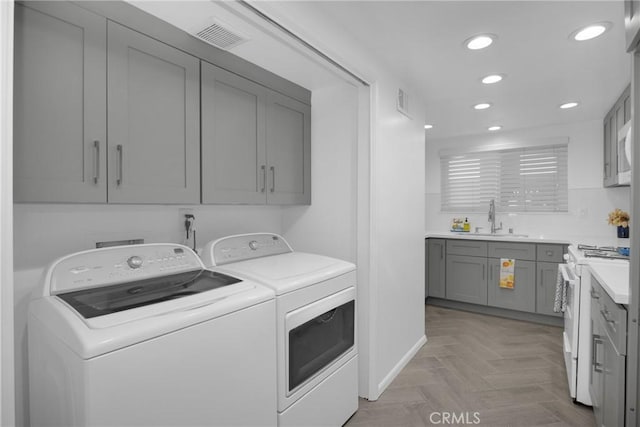 laundry room featuring separate washer and dryer, light parquet floors, and sink