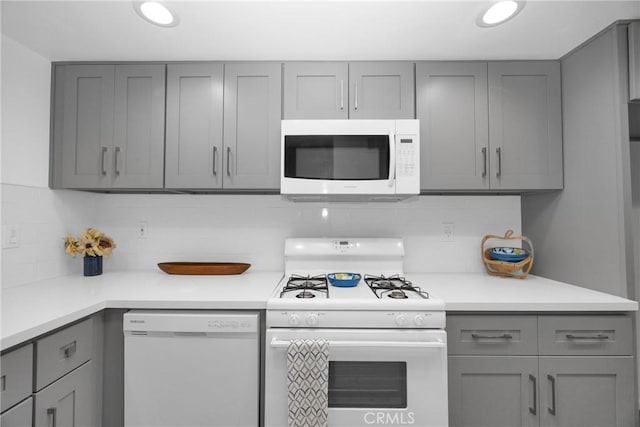 kitchen featuring backsplash, white appliances, and gray cabinets