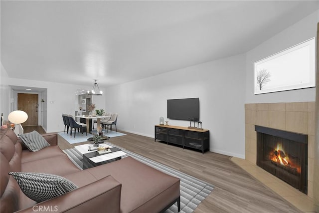 living room with light hardwood / wood-style floors, an inviting chandelier, and a fireplace