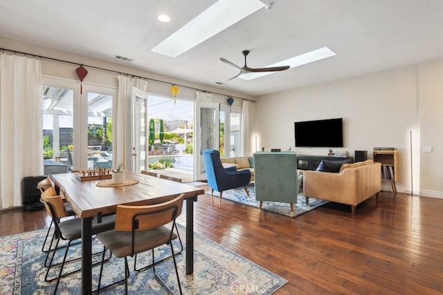 dining room with a skylight, ceiling fan, and dark hardwood / wood-style flooring