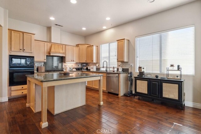 kitchen with a center island, tasteful backsplash, dark hardwood / wood-style flooring, dark stone countertops, and black appliances