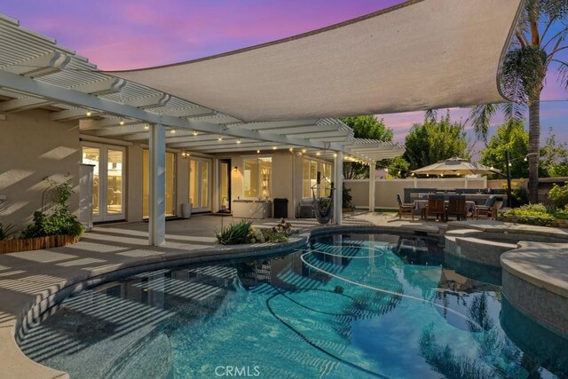 pool at dusk with a patio area and a pergola