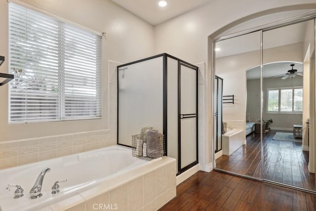 bathroom featuring ceiling fan, hardwood / wood-style floors, and plus walk in shower